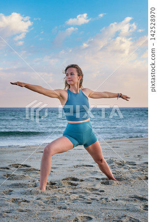 Front view of Virabhadrasana 2 yoga beside breaking waves Front view of Virabhadrasana 2 yoga beside breaking waves 142528970
