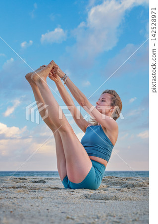 Ubhaya Padangusthasana yoga with both legs raised on the beach Ubhaya Padangusthasana yoga with both legs raised on the beach 142528971