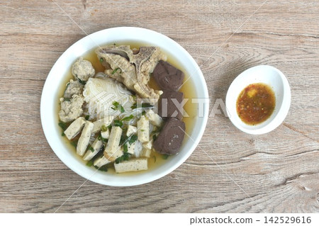 Vietnamese rice noodles or Pho with slice sausage and chop pork couple blood topping bone in soup on plate dipping spicy sour chili sauce 142529616