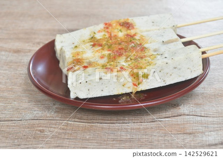 slice steamed mashed pork sausage Vietnamese style stabing wooden stick dipping spicy chili sauce on plate 142529621