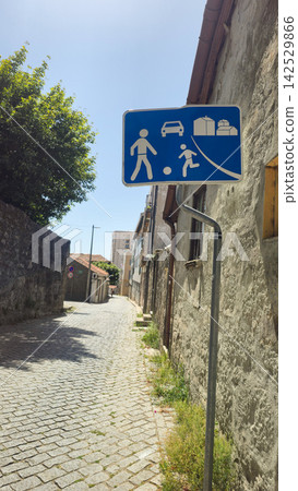 Blue residential street sign marks a shared pedestrian and vehicle zone in Portugal. Concepts: road safety, urban mobility, traffic regulation, pedestrian priority, European infrastructure. Blue residential street sign marks a shared pedestrian and vehicle zone in Portugal. Concepts: road safety, urban mobility, traffic regulation, pedestrian priority, European infrastructure. 142529866