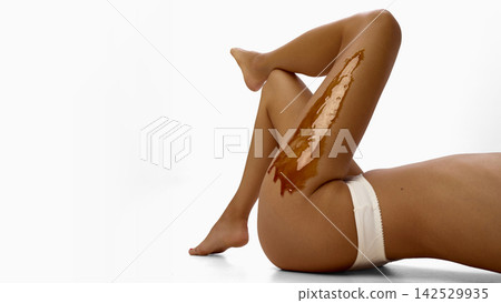 Female legs with applied wax along thigh while lying on white floor. Female legs with applied wax along thigh while lying on white floor. 142529935