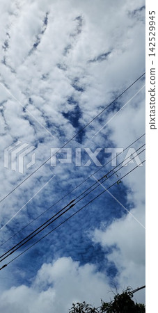 Interesting clouds in the blue sky seen over the power lines Interesting clouds in the blue sky seen over the power lines 142529945