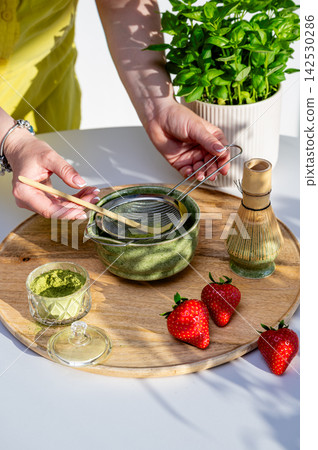 Hands Whisking Matcha to Frothy Consistency with Strawberries Hands Whisking Matcha to Frothy Consistency with Strawberries 142530286