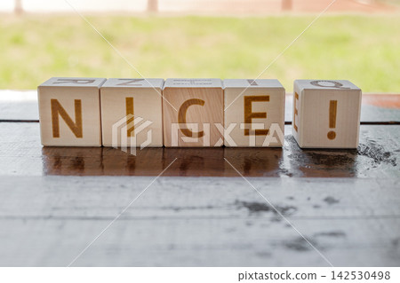 motivational word Nice ! is laid out from letters on wooden cubes motivational word Nice ! is laid out from letters on wooden cubes 142530498
