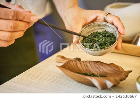 Hands preparing green tea leaves for traditional ceremony Hands preparing green tea leaves for traditional ceremony 142530667