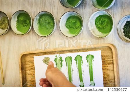Hand comparing matcha powder color grades and quality Hand comparing matcha powder color grades and quality 142530677