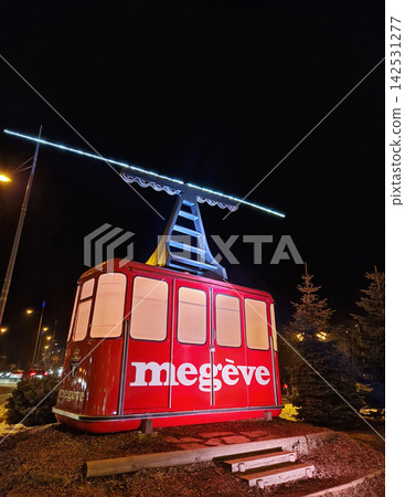 Megeve, France - December 27, 2025: A vintage red cable car displayed as a illuminated street installation at night as iconic ski resort symbol in the Haute-Savoie region of the French Alps Megeve, France - December 27, 2025: A vintage red cable car displayed as a illuminated street installation at night as iconic ski resort symbol in the Haute-Savoie region of the French Alps 142531277