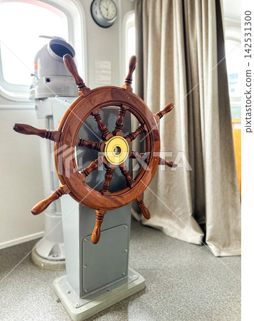 Vertical image. Wooden ship wheel inside of captain cabin Vertical image. Wooden ship wheel inside of captain cabin 142531300