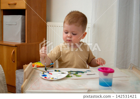 Toddler using hands and brush to create art. Fine and gross motor skills grow. Art therapy through free expression. Early childhood creativity without digital distractions Toddler using hands and brush to create art. Fine and gross motor skills grow. Art therapy through free expression. Early childhood creativity without digital distractions 142531421
