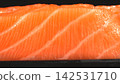 Eye level closeup shot of fresh raw salmon steak displaying parallel white fat lines and tender orange flesh 142531710