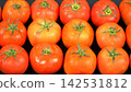 Top view of fresh ripe red tomatoes with green stems arranged in grid rows on black background, organic farm harvest produce 142531812