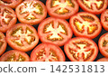 Macro shot of fresh juicy red tomato round slices arranged together, glistening cross section pulp and seed background 142531813