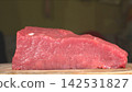 Eye level shot of whole fresh raw beef tenderloin block resting on rustic wooden cutting board, gourmet cooking ingredient 142531827