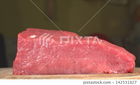Eye level shot of whole fresh raw beef tenderloin block resting on rustic wooden cutting board, gourmet cooking ingredient Eye level shot of whole fresh raw beef tenderloin block resting on rustic wooden cutting board, gourmet cooking ingredient 142531827