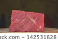 Eye level closeup of raw beef steak cut showing diagonal grain muscle fibers and tender texture on wooden board 142531828