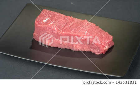 Prime cut fresh raw beef tenderloin steak portion served on modern black rectangular plate, gourmet culinary ingredient Prime cut fresh raw beef tenderloin steak portion served on modern black rectangular plate, gourmet culinary ingredient 142531831