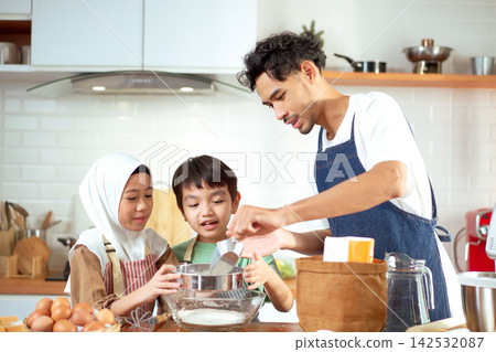 Happy Muslim father baking and sifting flour with his children in the kitchen Happy Muslim father baking and sifting flour with his children in the kitchen 142532087