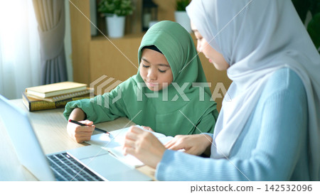 Muslim mother helping her daughter with homework at home Muslim mother helping her daughter with homework at home 142532096