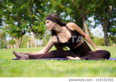 Hispanic woman stretching leg in seated head to knee pose on mat in park Hispanic woman stretching leg in seated head to knee pose on mat in park 142532560