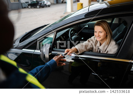 Woman paying for service with credit card at drive-thru Woman paying for service with credit card at drive-thru 142533618