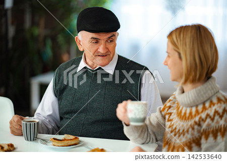 Senior man and adult daughter talking over coffee Senior man and adult daughter talking over coffee 142533640