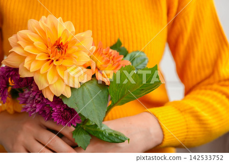 Woman showing into camera yellow dahlia Autumn garden colorful flowers. Beautiful autumnal bouquet dahlia chrysanthemum. Red pink orange fall color fall floral background. Flower shop and florist Woman showing into camera yellow dahlia Autumn garden colorful flowers. Beautiful autumnal bouquet dahlia chrysanthemum. Red pink orange fall color fall floral background. Flower shop and florist 142533752