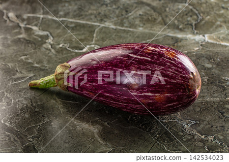 Striped purple eggplant on dark marble surface 142534023