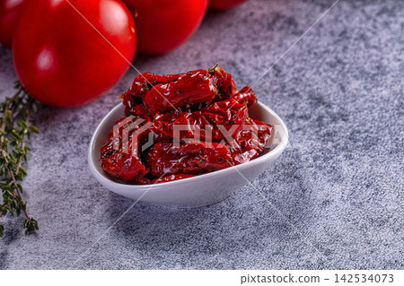 Sun dried tomatoes in white bowl with fresh thyme and whole tomatoes on textured gray surface Sun dried tomatoes in white bowl with fresh thyme and whole tomatoes on textured gray surface 142534073