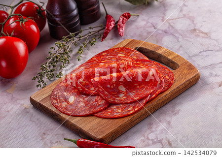 Sliced salami on wooden cutting board with fresh tomatoes and red chili peppers Sliced salami on wooden cutting board with fresh tomatoes and red chili peppers 142534079
