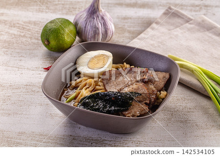 Beef ramen bowl with soft boiled egg, nori, lime, and garlic on rustic surface Beef ramen bowl with soft boiled egg, nori, lime, and garlic on rustic surface 142534105