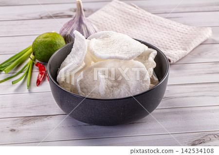 Crispy pork rinds in black bowl with lime garlic and chili on wooden table Crispy pork rinds in black bowl with lime garlic and chili on wooden table 142534108