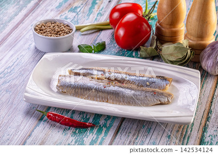Salted herring fillets on white plate with tomatoes, garlic, chili and spices on rustic wooden table Salted herring fillets on white plate with tomatoes, garlic, chili and spices on rustic wooden table 142534124