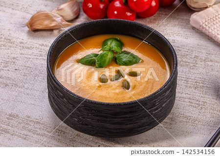 Creamy pumpkin soup in black ceramic bowl with basil and pumpkin seeds Creamy pumpkin soup in black ceramic bowl with basil and pumpkin seeds 142534156