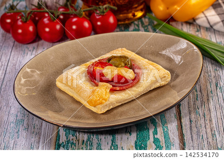 Savory puff pastry tart with tomato, salami, cheese, and jalapeno on rustic plate Savory puff pastry tart with tomato, salami, cheese, and jalapeno on rustic plate 142534170