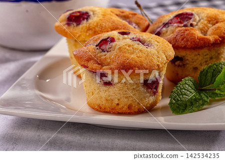 Cherry muffins on white plate with mint garnish Cherry muffins on white plate with mint garnish 142534235