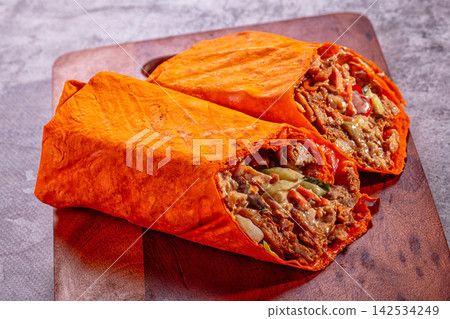 Chicken shawarma wrap cut in half on wooden board Chicken shawarma wrap cut in half on wooden board 142534249