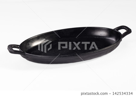 Black cast iron oval baking dish with two handles on white background Black cast iron oval baking dish with two handles on white background 142534334
