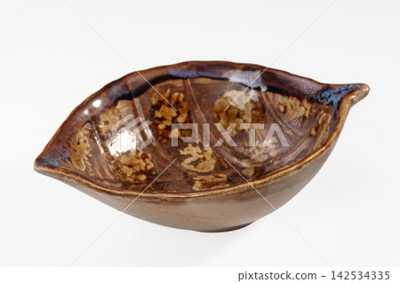 Handcrafted ceramic bowl shaped like leaf with brown glaze and speckled texture Handcrafted ceramic bowl shaped like leaf with brown glaze and speckled texture 142534335
