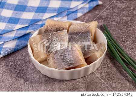 Salted herring fillets in white bowl with blue checkered cloth and chives Salted herring fillets in white bowl with blue checkered cloth and chives 142534342