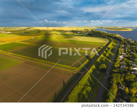 High angle wide horizontal aerial drone photograph of polder fields, grass dike road, holiday park chalets, and Lake Veere in Kamperland, Zeeland, Netherlands in golden hour summer light High angle wide horizontal aerial drone photograph of polder fields, grass dike road, holiday park chalets, and Lake Veere in Kamperland, Zeeland, Netherlands in golden hour summer light 142534386
