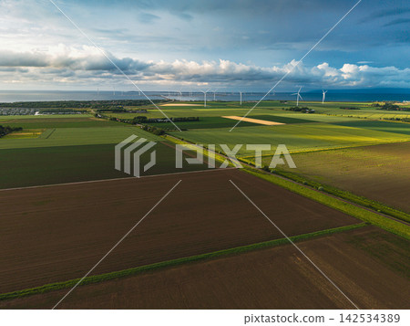 High angle wide horizontal aerial drone photograph of polder fields, grass dike, wind turbines, storm barrier, and sea in Neeltje Jans, Zeeland, Netherlands in golden hour summer light High angle wide horizontal aerial drone photograph of polder fields, grass dike, wind turbines, storm barrier, and sea in Neeltje Jans, Zeeland, Netherlands in golden hour summer light 142534389