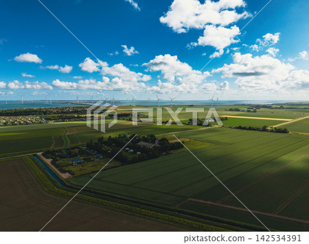 High angle wide horizontal aerial drone photograph of polder fields, farmstead campsite, wind turbines, storm barrier, and sea in Neeltje Jans, Zeeland, Netherlands on sunny summer day High angle wide horizontal aerial drone photograph of polder fields, farmstead campsite, wind turbines, storm barrier, and sea in Neeltje Jans, Zeeland, Netherlands on sunny summer day 142534391