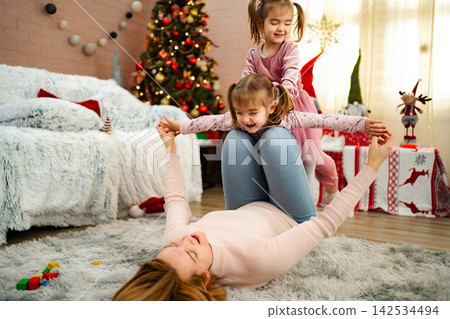 Mother playing with happy daughters during Christmas holidays Mother playing with happy daughters during Christmas holidays 142534494