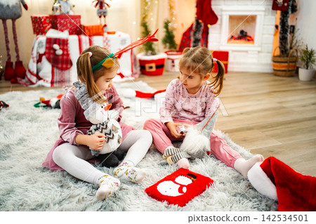 Two young girls playing with Christmas toys in festive home Two young girls playing with Christmas toys in festive home 142534501