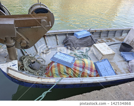 Deck of a small commercial fishing boat with equipment and crates docked in the harbor Deck of a small commercial fishing boat with equipment and crates docked in the harbor 142534868