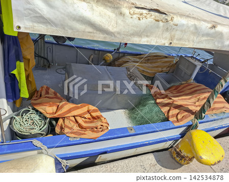 Boat deck with canvas awning, fishing nets, and colorful cloths in a marina setting Boat deck with canvas awning, fishing nets, and colorful cloths in a marina setting 142534878