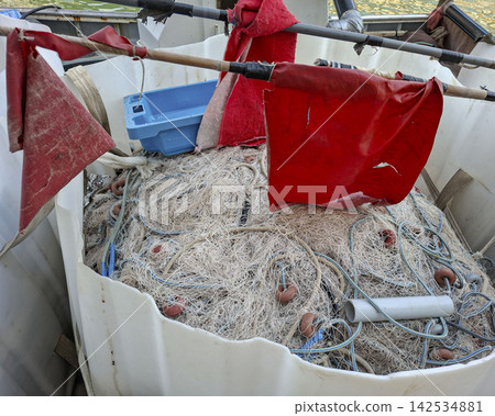 Commercial fishing gear with tangled nets and red marker flags inside a container on a fishing boat Commercial fishing gear with tangled nets and red marker flags inside a container on a fishing boat 142534881