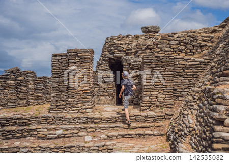 Boy tourist climbing ancient stone ruins at Tonina archaeological site in Chiapas Mexico with pre Hispanic history stone walls cultural heritage Mexican archaeology and looking at camera. Boy tourist climbing ancient stone ruins at Tonina archaeological site in Chiapas Mexico with pre Hispanic history stone walls cultural heritage Mexican archaeology and looking at camera. 142535082