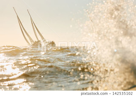 sailing boat is in sailing regatta in the Gulf of Finland, Russia, St.Petersburg, Yachtsmen are sitting amicably on board the boat at incredible sunset, magic splashing water, teamwork sailing boat is in sailing regatta in the Gulf of Finland, Russia, St.Petersburg, Yachtsmen are sitting amicably on board the boat at incredible sunset, magic splashing water, teamwork 142535102